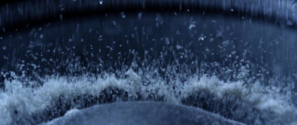 White dust jumping up and down on the surface of a vibrating speaker