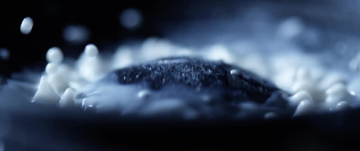 A layer of white liquid vibrating over the diaphragm of a speaker