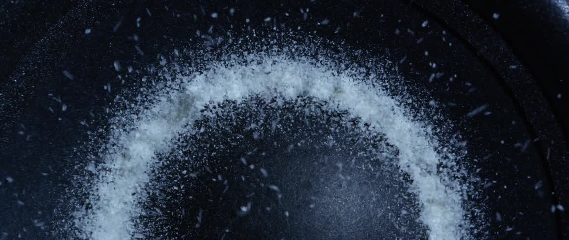 White small grains jumping and moving inside a black mate vibrating pan
