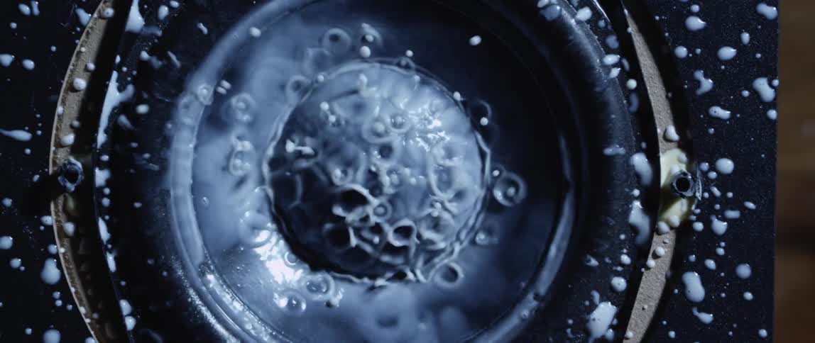 White thick liquid splashing over the surface of a vibrating speaker