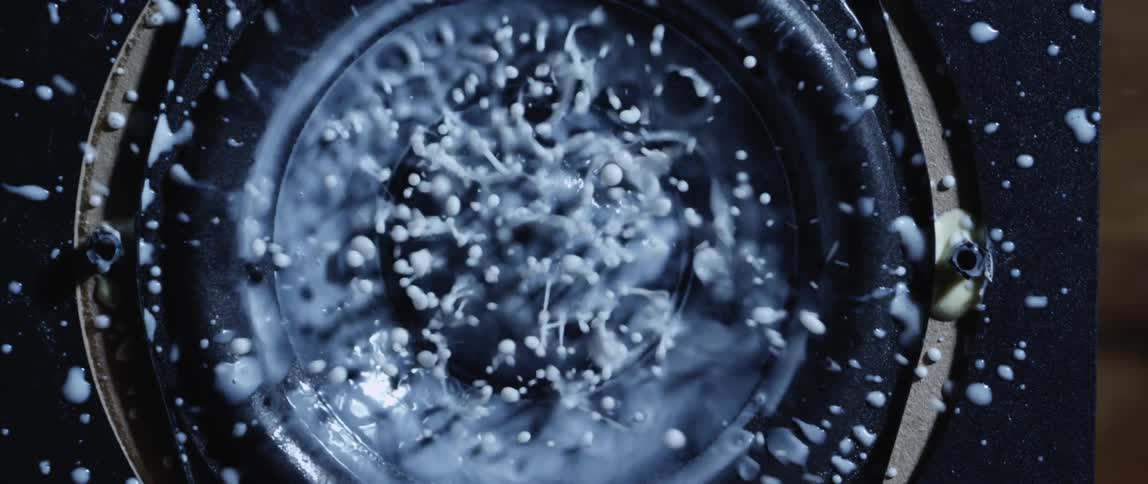 White thick liquid vibrating and splashing on the surface of a speaker