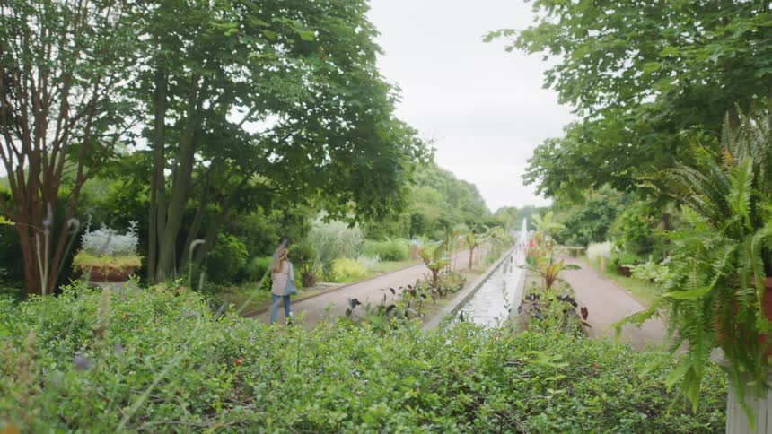 Woman walking on the path near a garden on a park