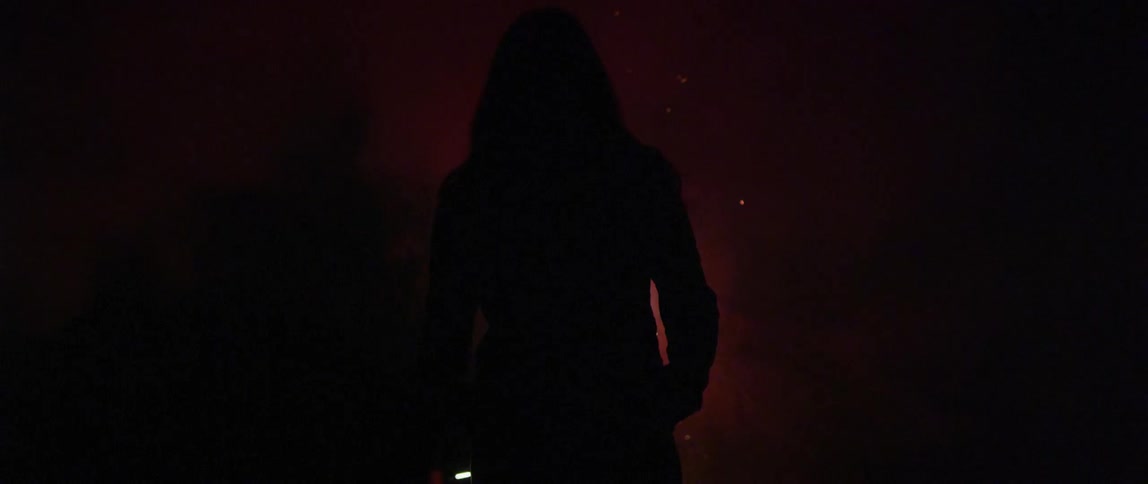 A person is standing in darkness as fireworks are going off