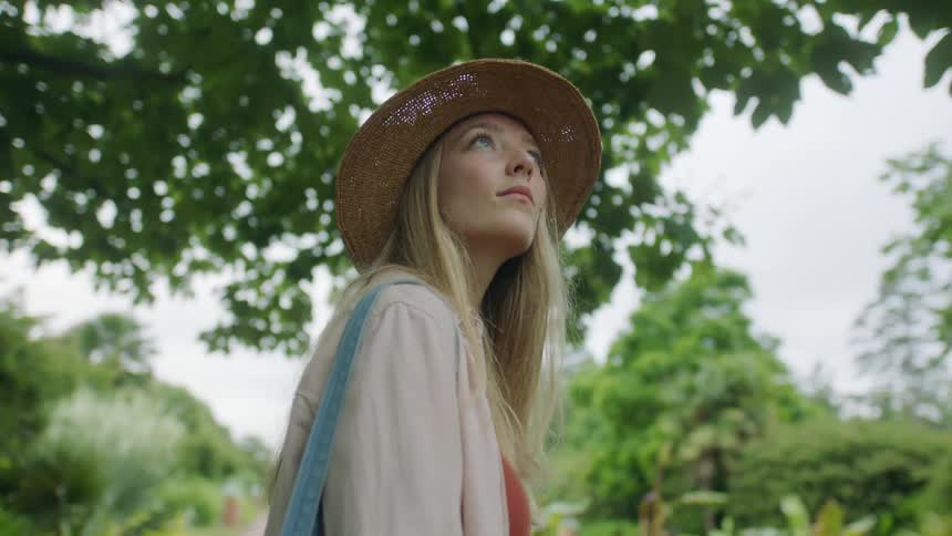 A woman is walking outdoors surrounded by trees