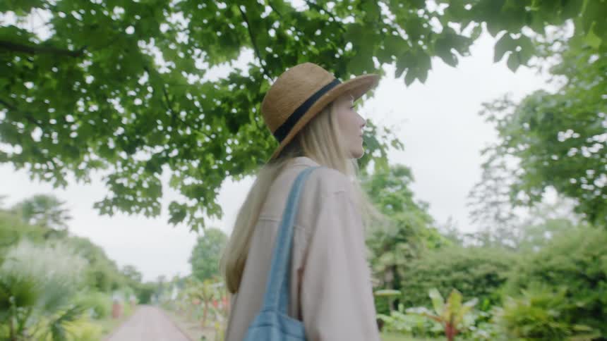 A young woman gazes around at her surroundings while standing on a walkway outdoors during the day
