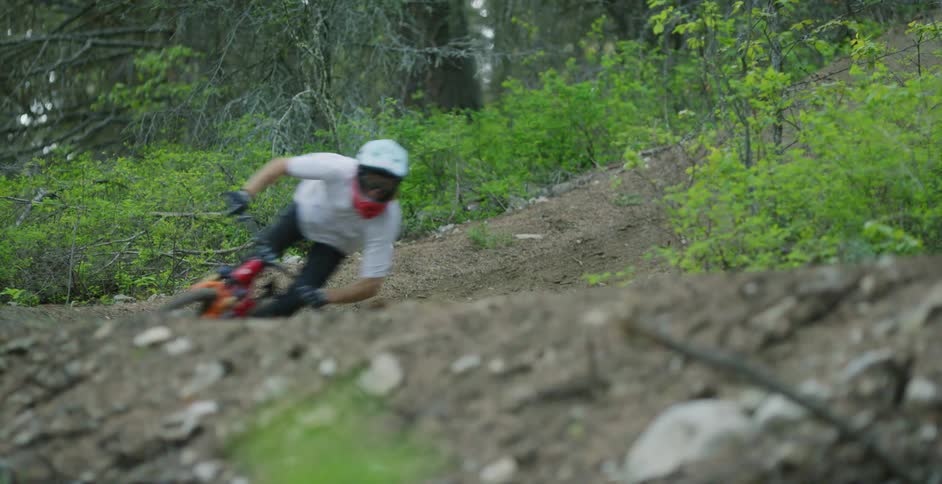 A teenager races his mountain bike down a hill in a forest