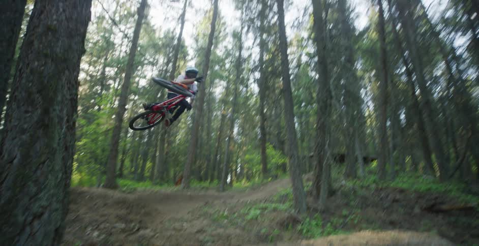 Cyclist driving a mountain bicycle in a dirt track through the forest downhill