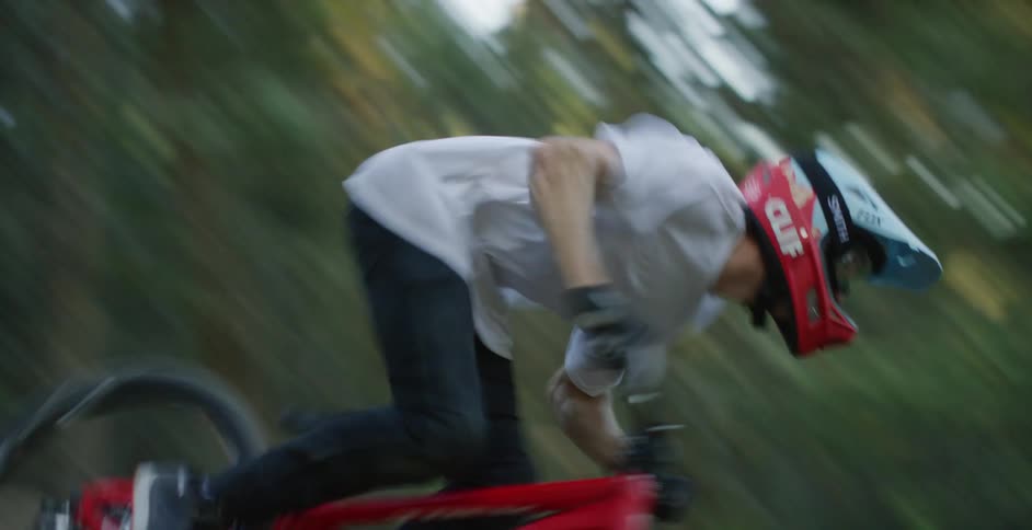 A person with a helmet riding a bike in an obstacle course in the woods with trees the sky and clouds in the background