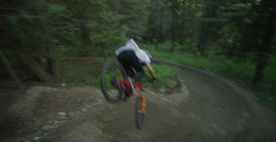 A boy rides a mountain bike on a dirt trail in the forest and does a trick with his bike by flipping it