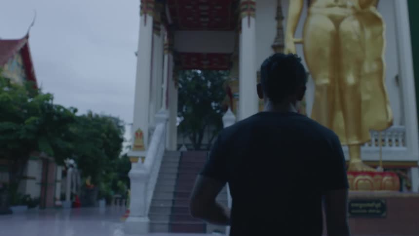 A man walks through the gates of a temple in the morning