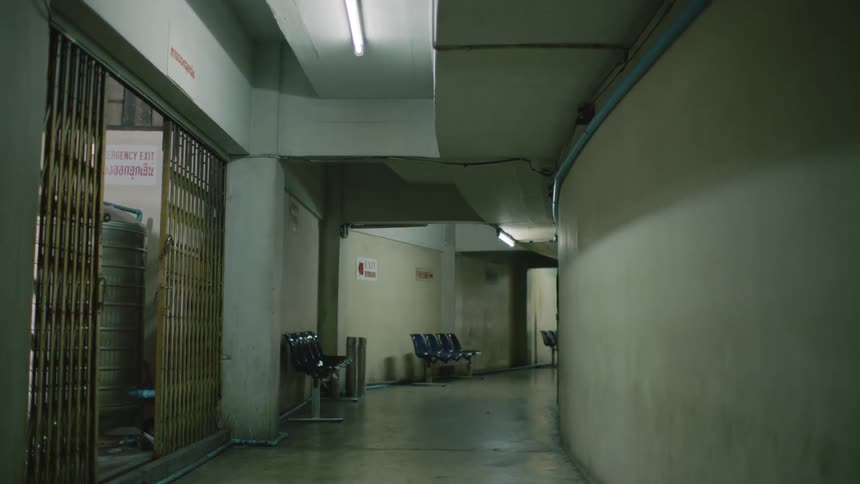 Curved corridor in a building with blue seats and a room on the right with a gold metal gate
