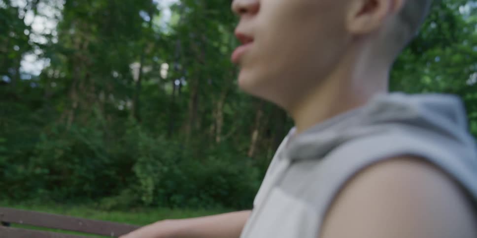 Two boys running and walking on a playground with trees the sky and clouds in the background