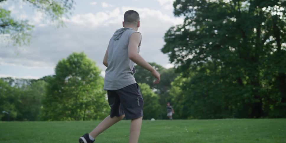 A young boy kicks a ball to his disabled friend
