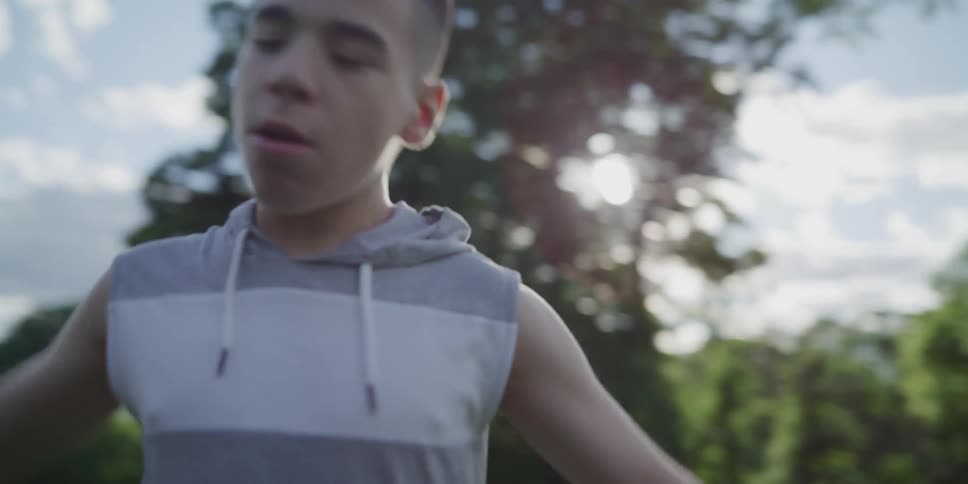 A boy holds his arms out as he dribbles a soccer ball and tries to keep it away from his brother