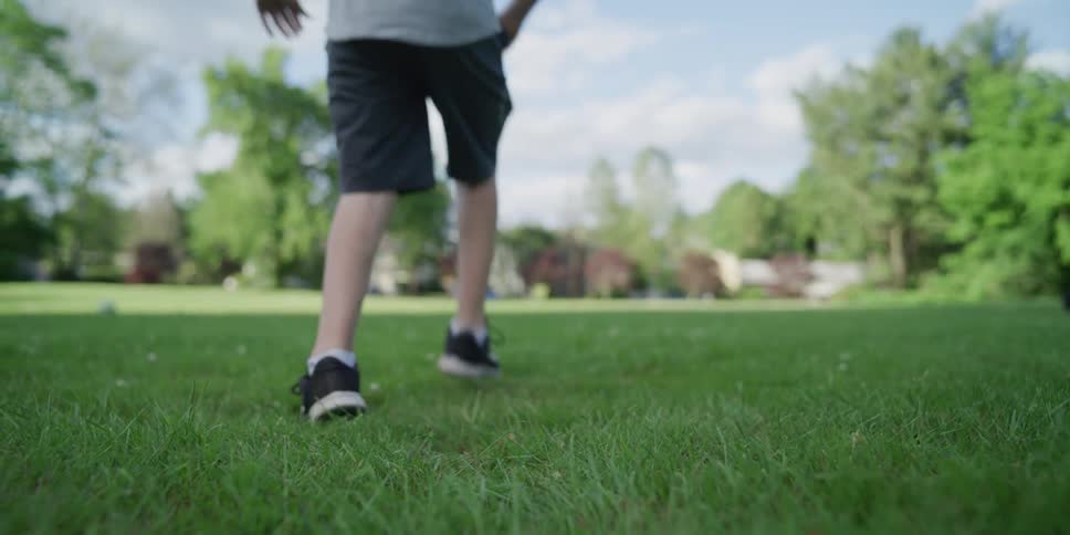 Teenage boy with cerebral palsy playing soccer with a friend on the lawn