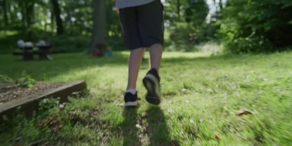 A boy walks behind another child in forest park