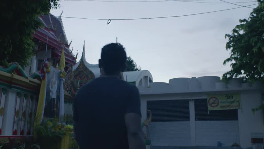 A man walks through a parking lot to an asian temple building at dusk