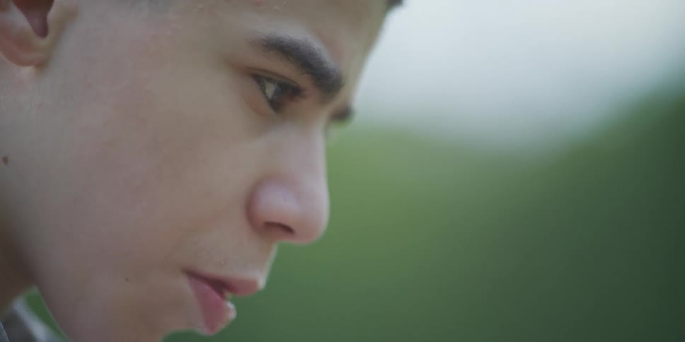 A hispanic male in his teens is looking at something with intense focus