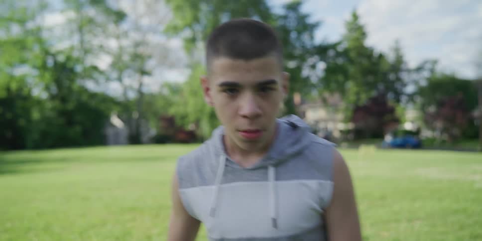 A disabled boy stands in a park with his friend and slowly walks