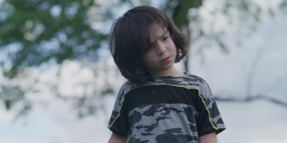 Young boy playing outdoors sits besides a teenage friend