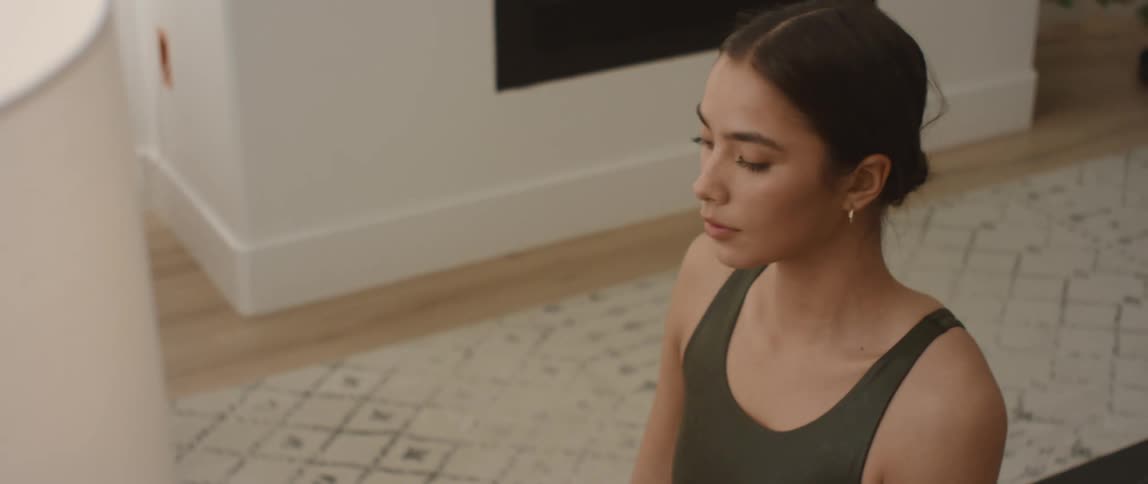 Woman on a yoga mat in a living room doing an upward stretch