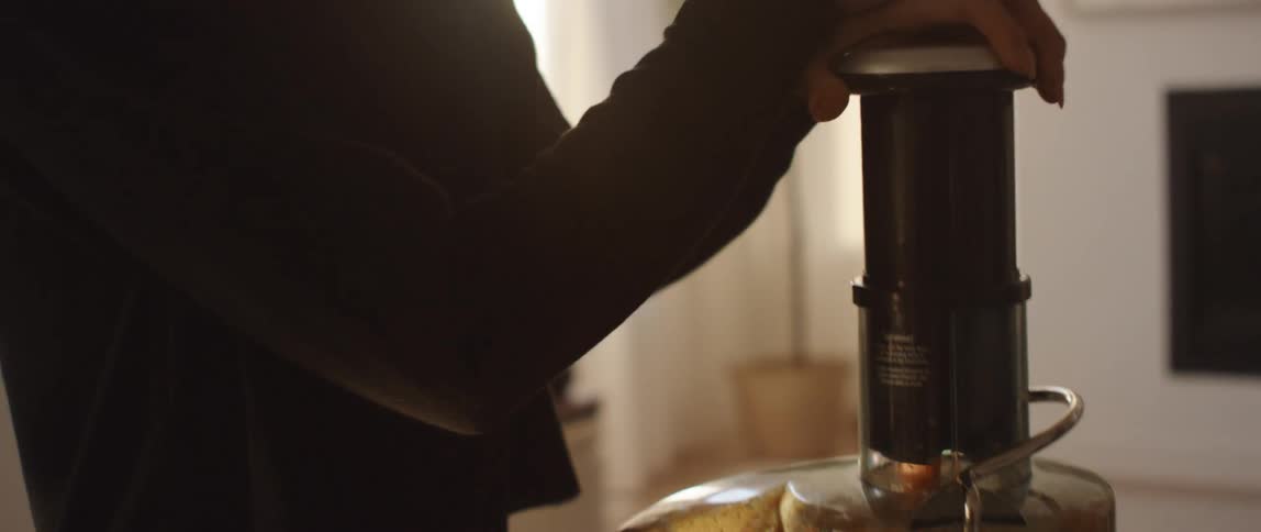 A woman making juice with a juicer