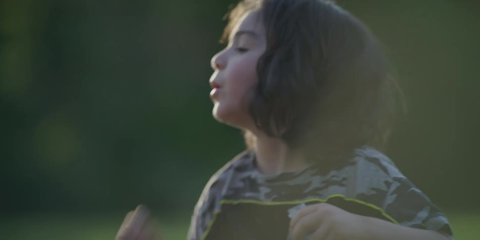 Tired boy sits besides a friend to drink water from a bottle outdoors
