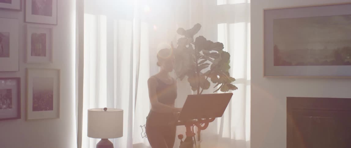 A woman programs her spin bike at home before exercising