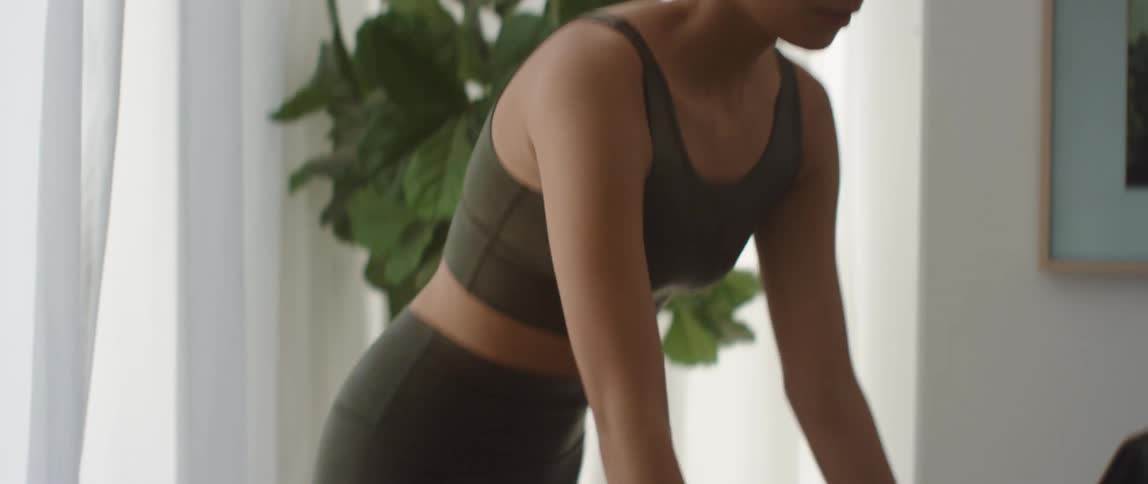 A woman exercises on a stationary bike in a room at home during the day
