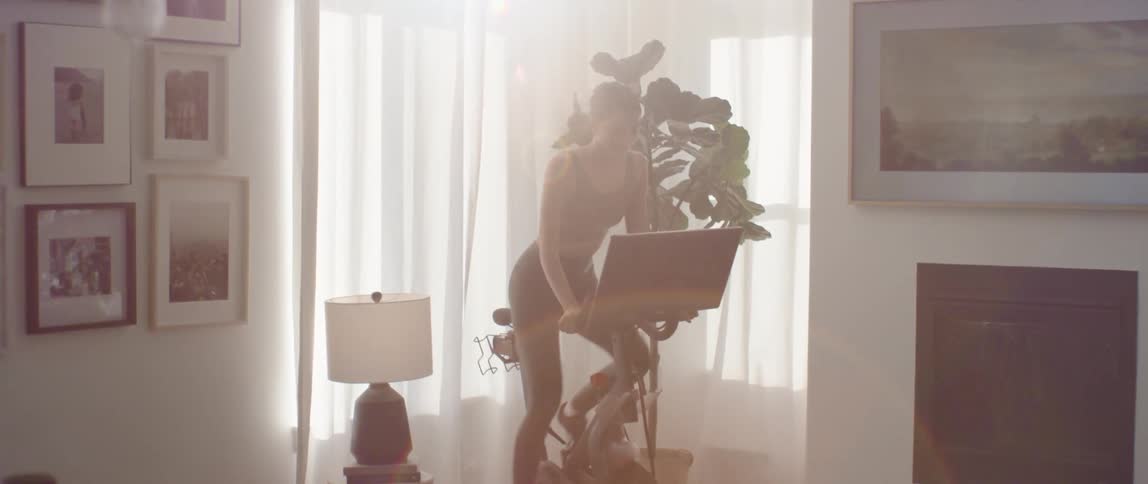 Woman riding on a stationary bike in a living room during the day