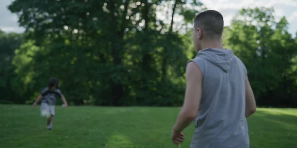 A pair of boys kick a soccer ball around a field of a grass on a sunny day