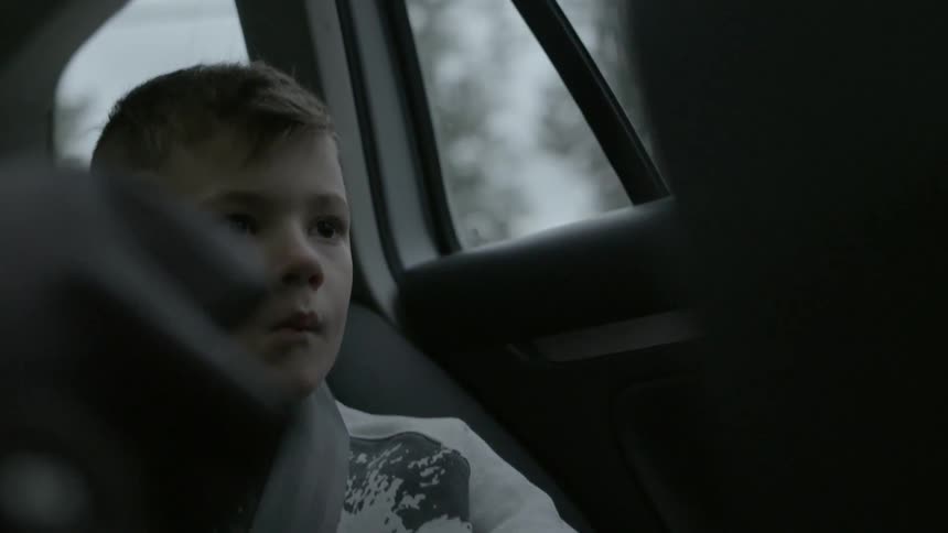 A boy riding in the backseat of a vehicle