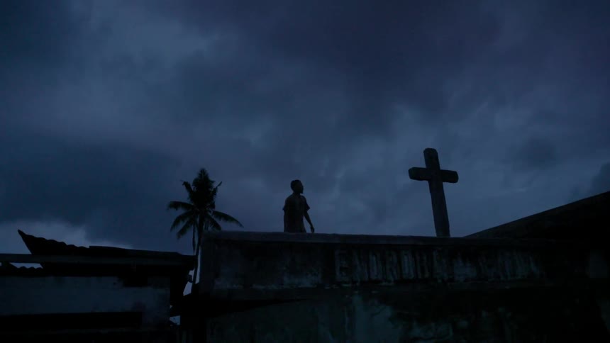 A man walks near a concrete cross