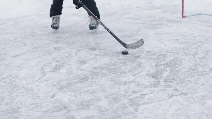 A person is skating on ice then he shoots a puck with his hockey stick
