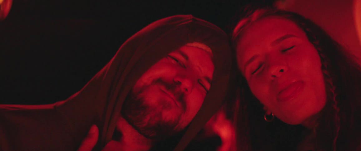 Man and a woman with their heads against each others smiling at the camera