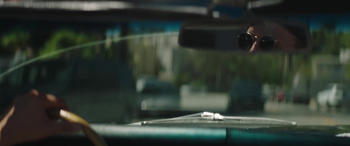 A man drives a vintage convertible through a city street