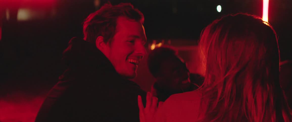 Young couple sitting outdoors under red lights have fun around a campfire