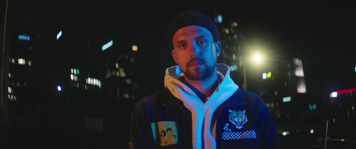 A man is standing outdoors in a city at night