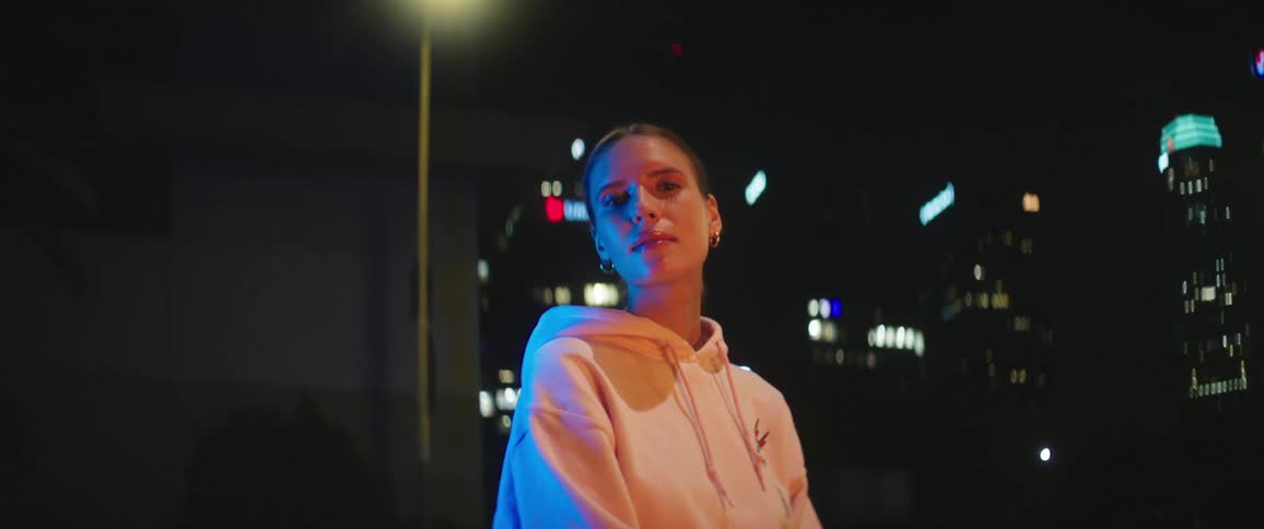 Young woman sitting outdoors in the city at night looking at the camera