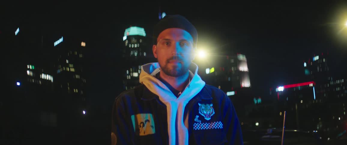 A man is standing outdoors in a city at night