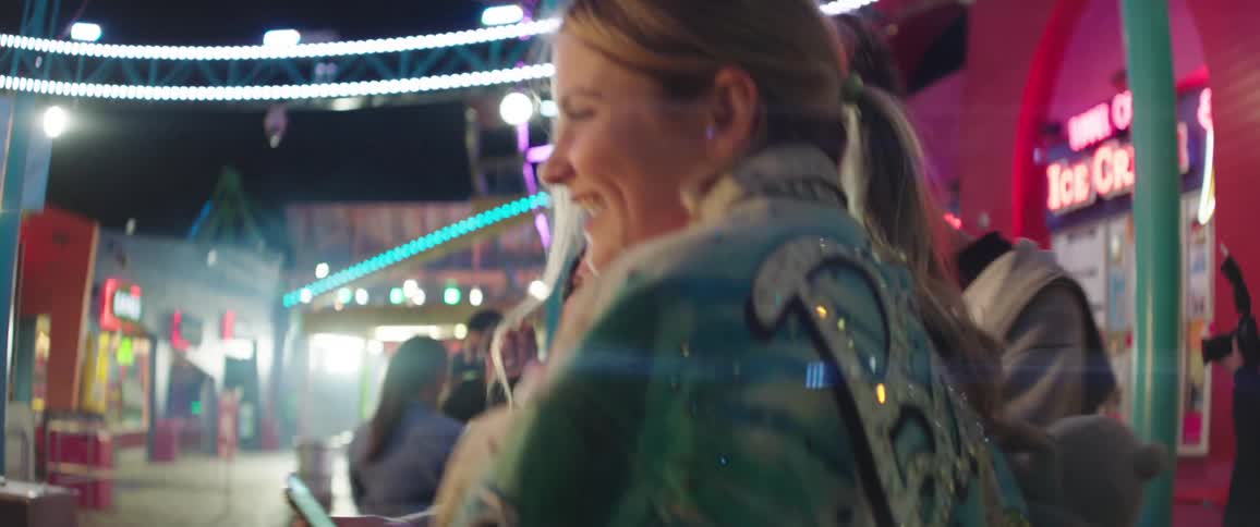 Couple dances with others at a fair as they record themselves on a cellphone