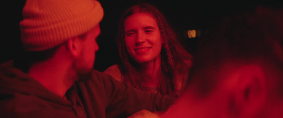 A male and female teenager sit outside talking and having fun at night