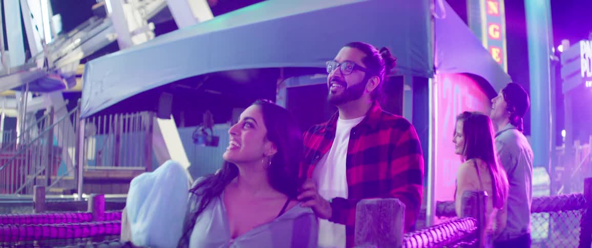 Two couples walk towards a ferris wheel at a carnival