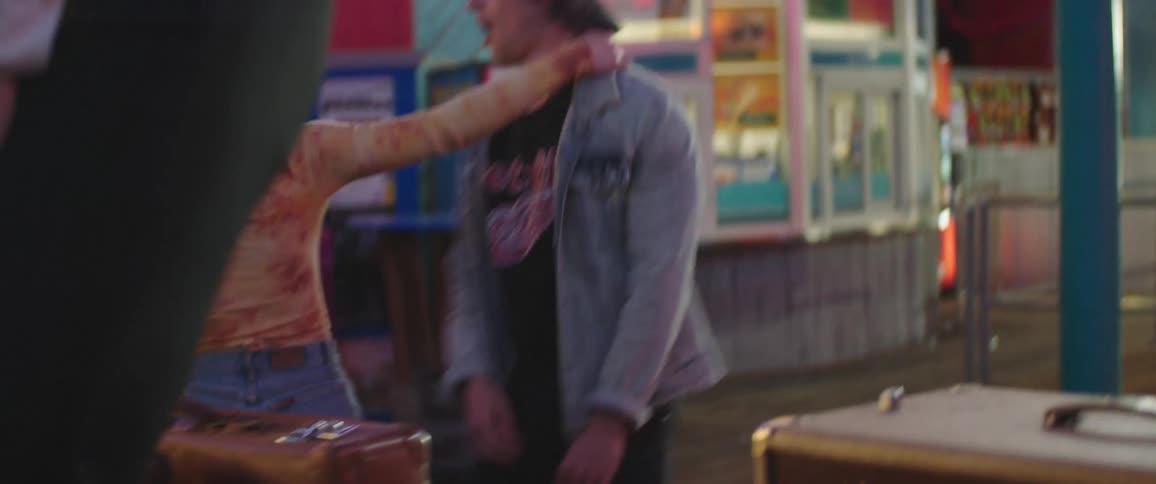 A couple of teenagers dance in the street in front of stores at night