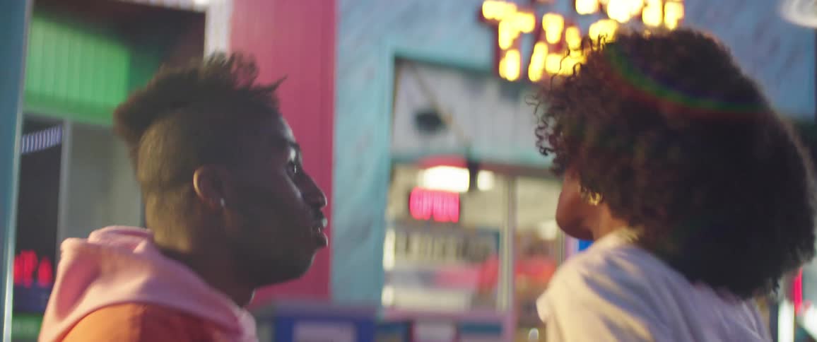 A man and a woman dancing and smiling with storefronts in the background