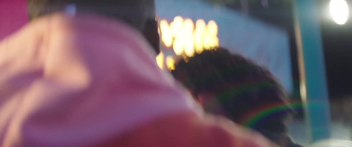 Young couple happily dancing on a colorful amusement park at night