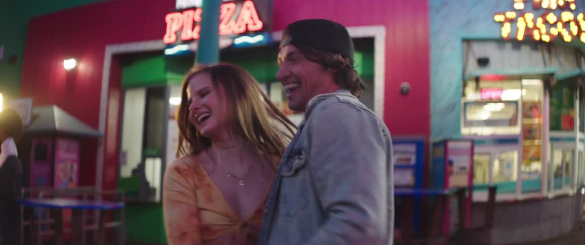A boyfriend and girlfriend dancing on an amusement park pier