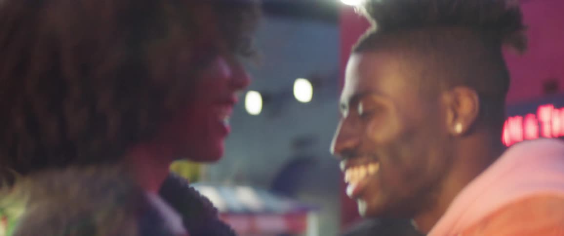 Young happy couple smile dancing on an amusement park at night