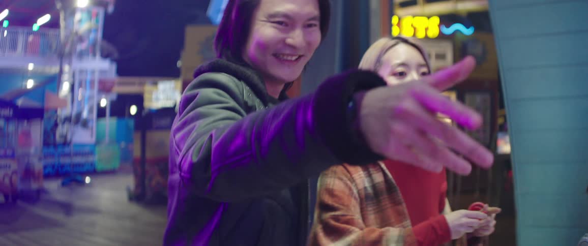 Couple plays ring toss game at outside arcade