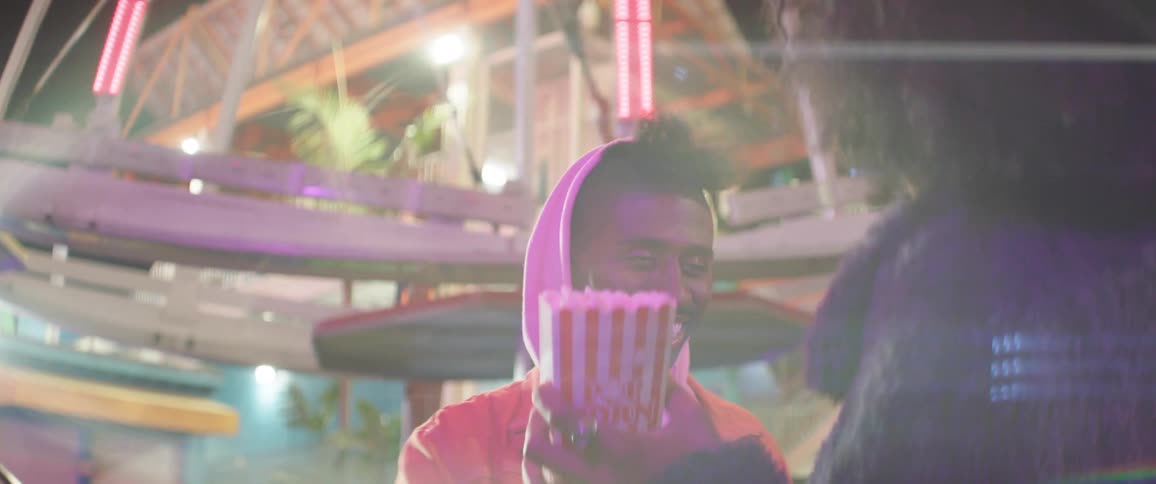 Man tries to throw a piece of popcorn into a womans mouth at a carnival
